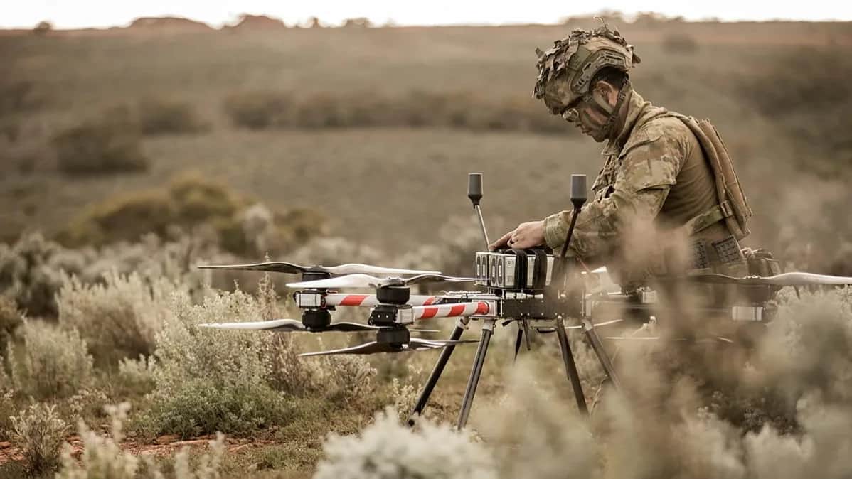An Australian soldier in camouflage preparing a Callisto in low outback scrub