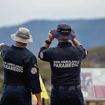Two NSW Ambulance paramedics at a lookout, one pointing out across the valley to the ranges