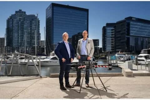 Ken King and Leonard Hall standing with a Callisto at a city marina
