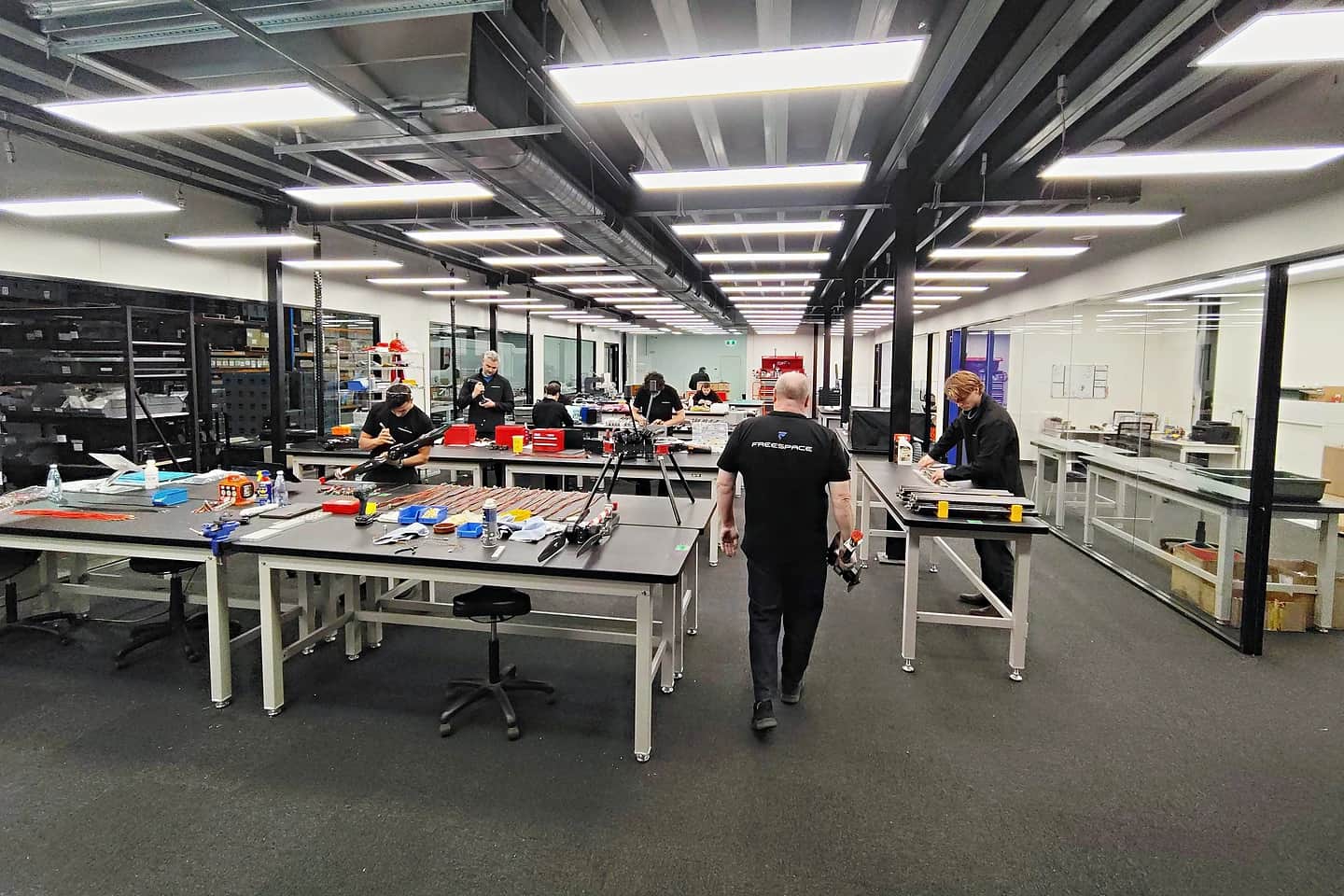 The Freespace production floor, technicians at benches assembling Callisto airframes