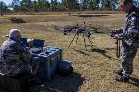 Two Royal Australian Navy personnel on grass with a Callisto and its ground station cases