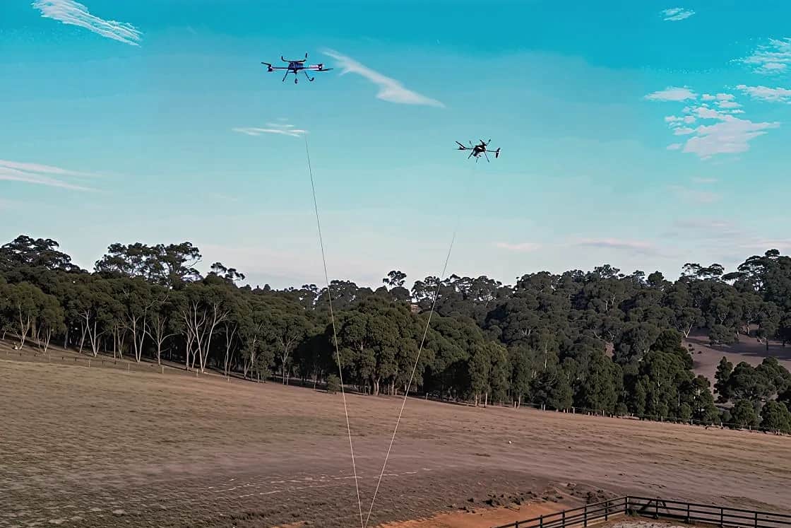 Two Callisto aircraft above a paddock, each on a line to one shared load