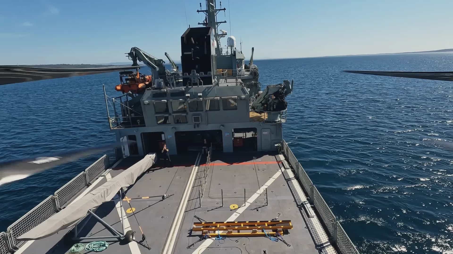 Looking down from a Callisto at a naval vessel's flight deck, its tether running to the deck