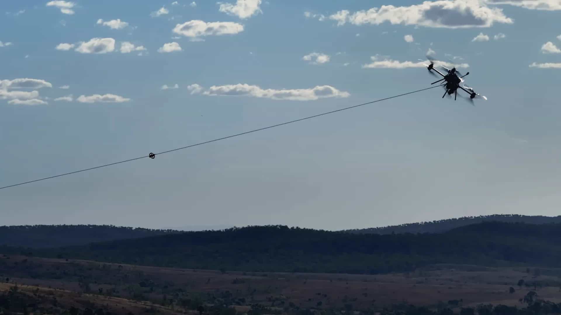 A Callisto pulling a pilot line across a valley, hills behind