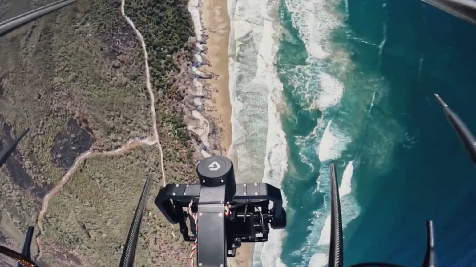 Looking straight down past a Callisto's gimbal camera at surf breaking on a beach