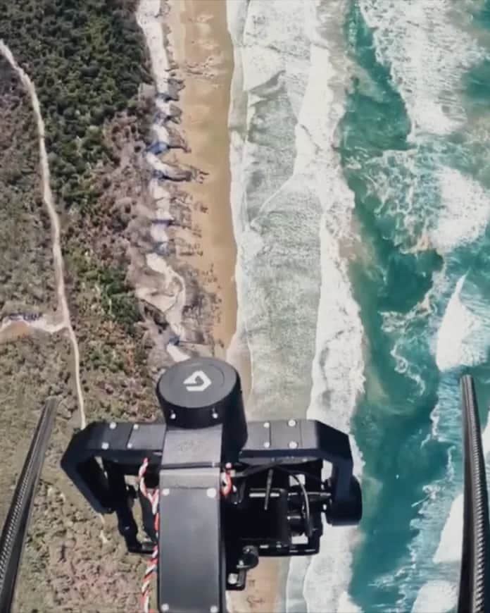 Looking straight down past a Callisto's gimbal camera at surf breaking on a beach