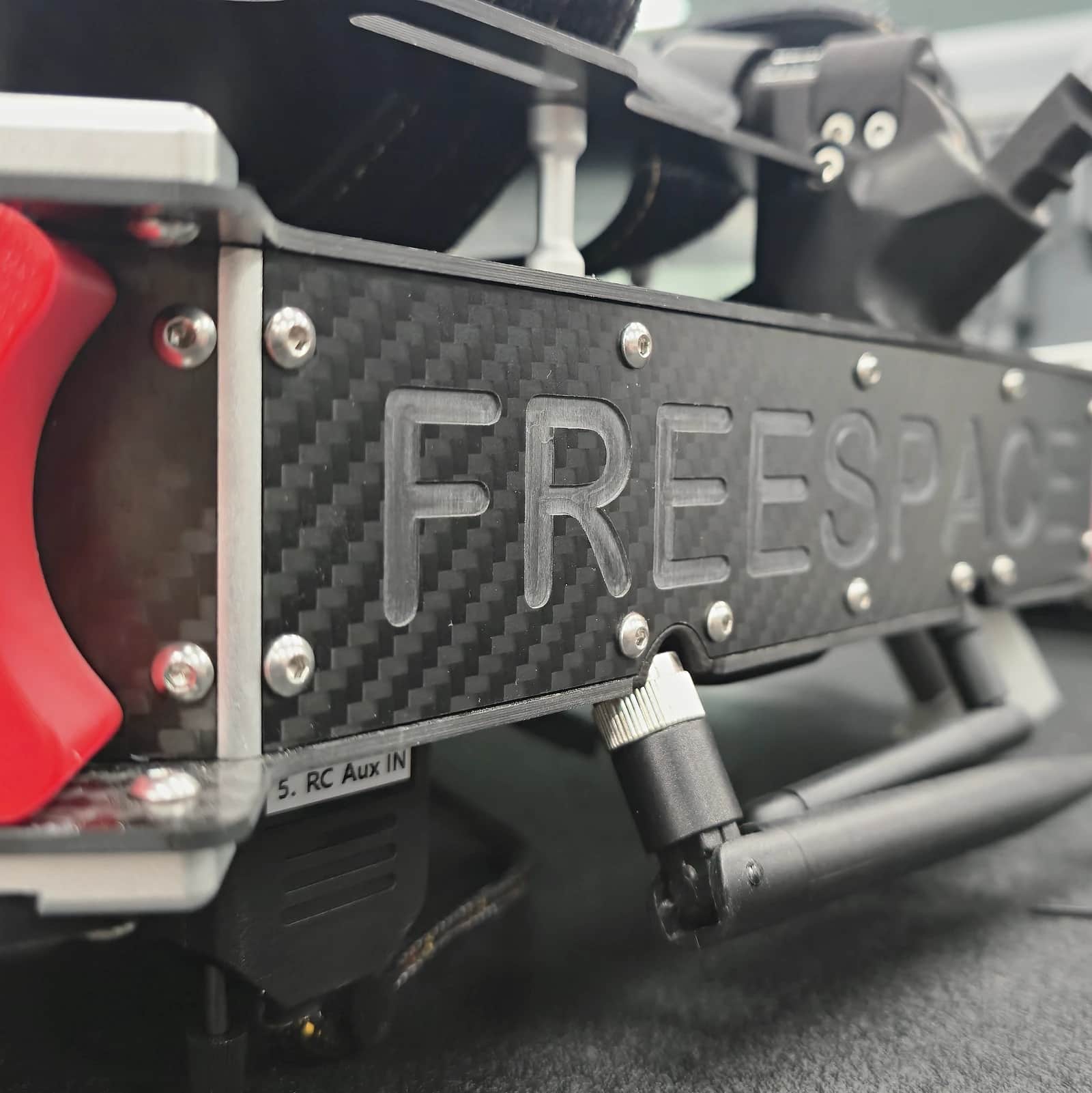 The Callisto's carbon fibre body plate embossed FREESPACE, its connectors and the red remove before flight cover beside it