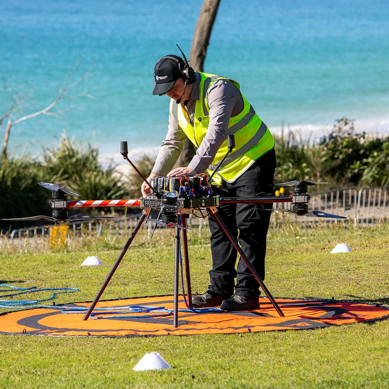 A technician in hi-vis preparing a Callisto on a landing pad above a beach