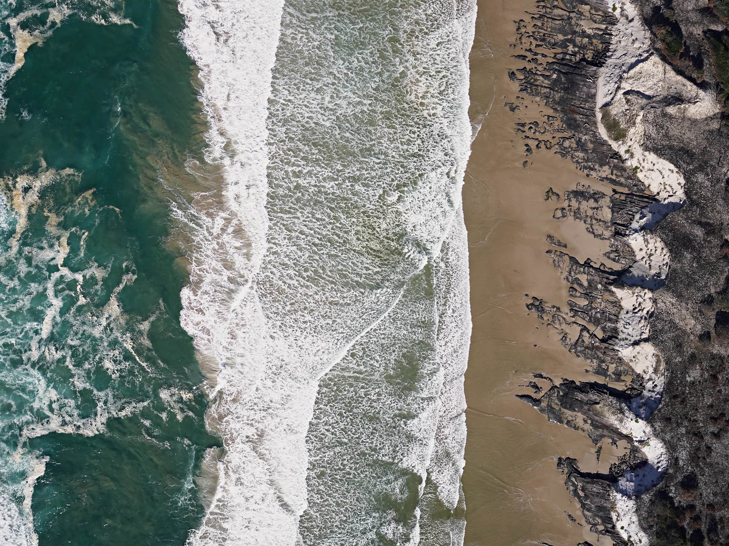 Looking straight down from a Callisto at surf breaking on a beach and dunes during a coastal search