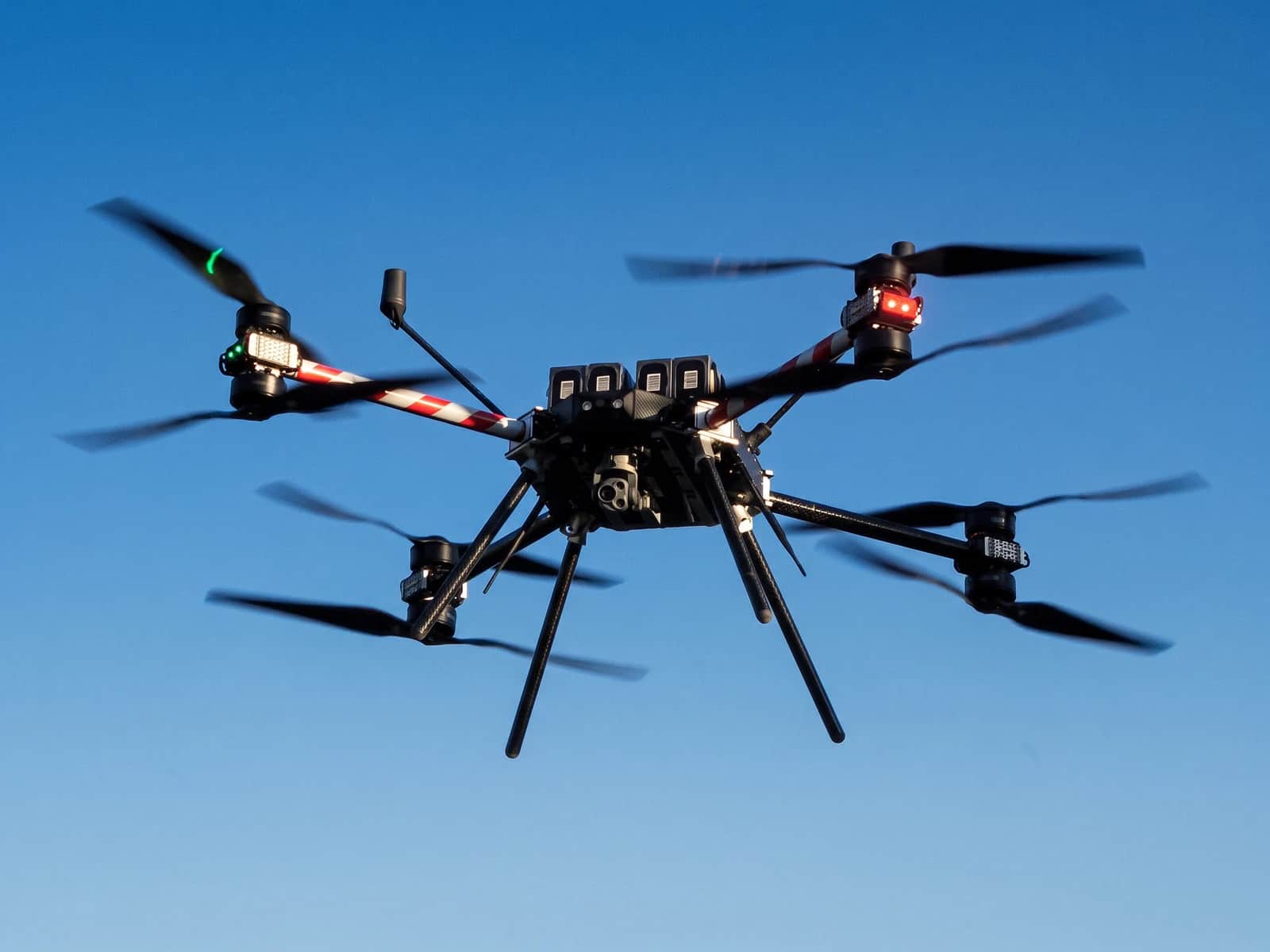 A Callisto 50 in flight against a clear blue sky, the AVT gimbal mounted beneath it