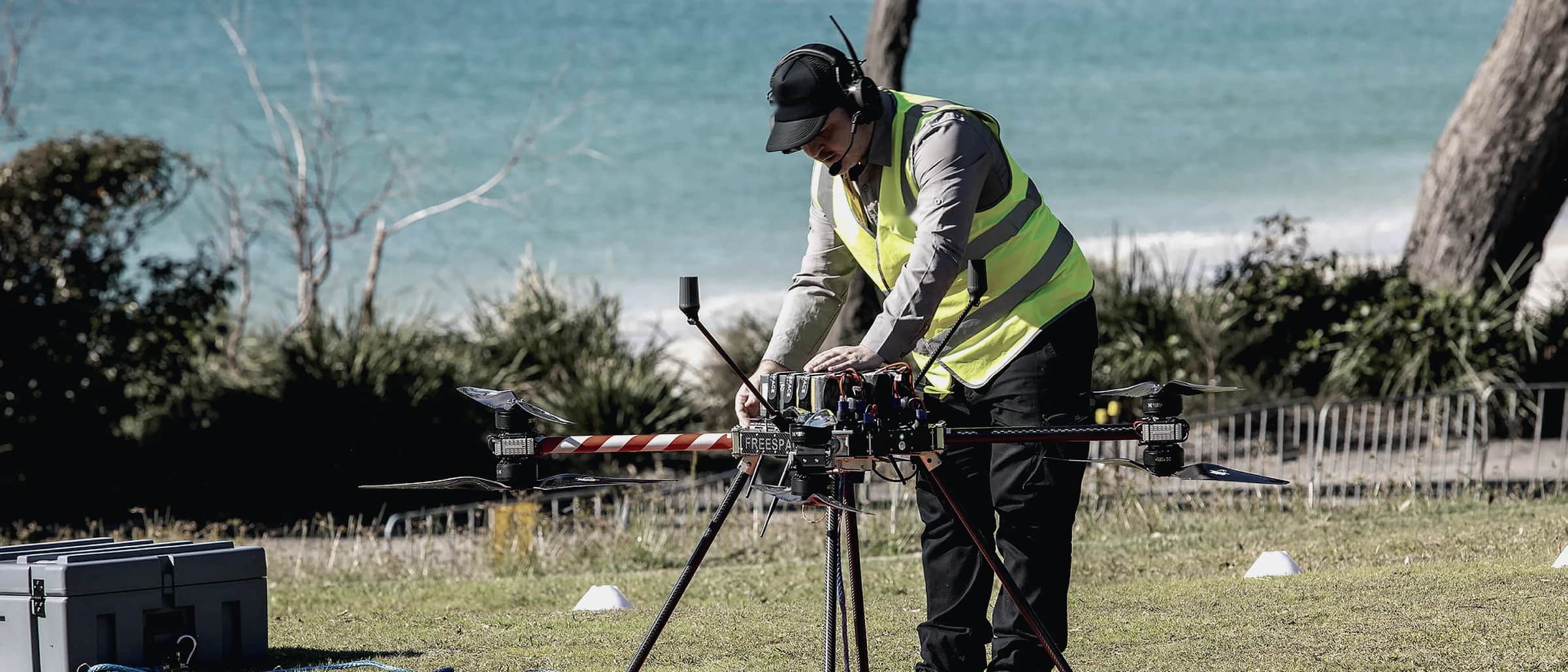 A technician in hi-vis preparing a Callisto on a landing pad above a beach